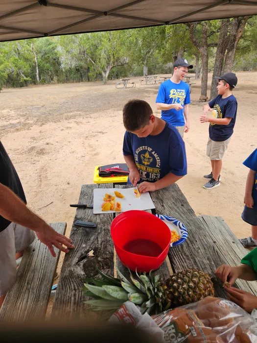 Scouts preparing food together at an outdoor picnic table